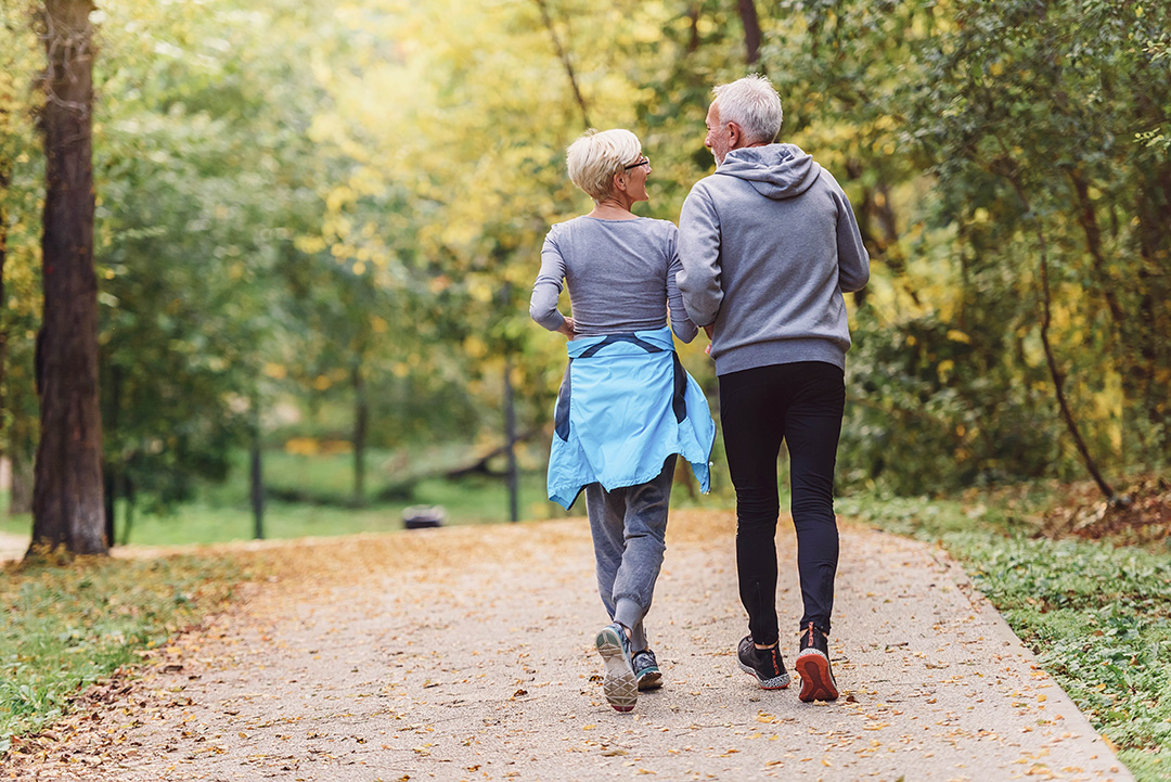 Ein Mann geht mit einer Frau durch einen Park joggen