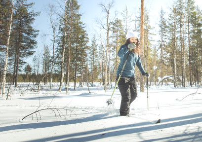 nainen lumikenkäilee metsässä levi