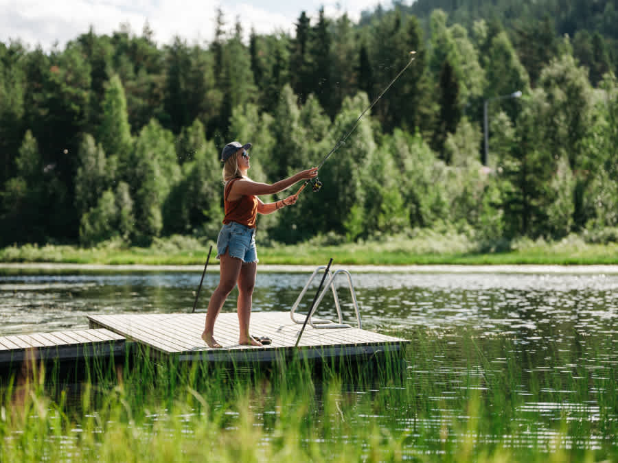 nainen kalastaa laiturilta