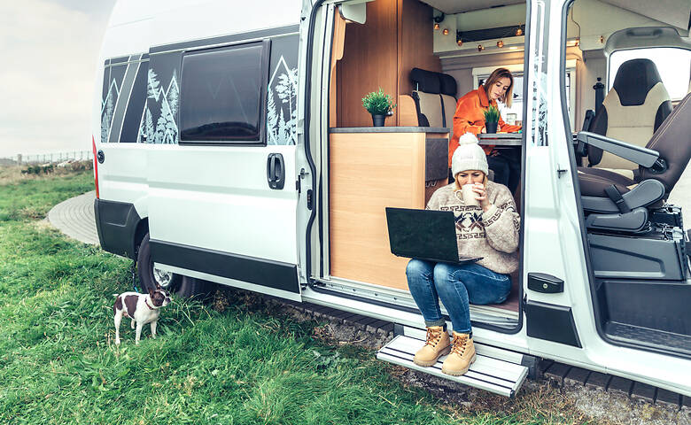 Zwei Frauen sitzen mit dem Laptop im Camper