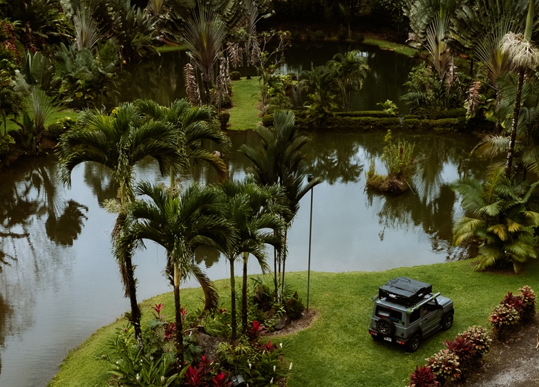 Camper parkt zwischen Pflanzen und Bäumen an einem See in Costa Rica