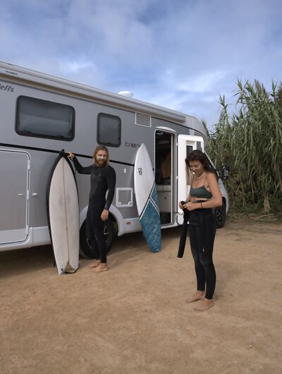 Paar mit Wohnmobil und Surfbrett in Portugal