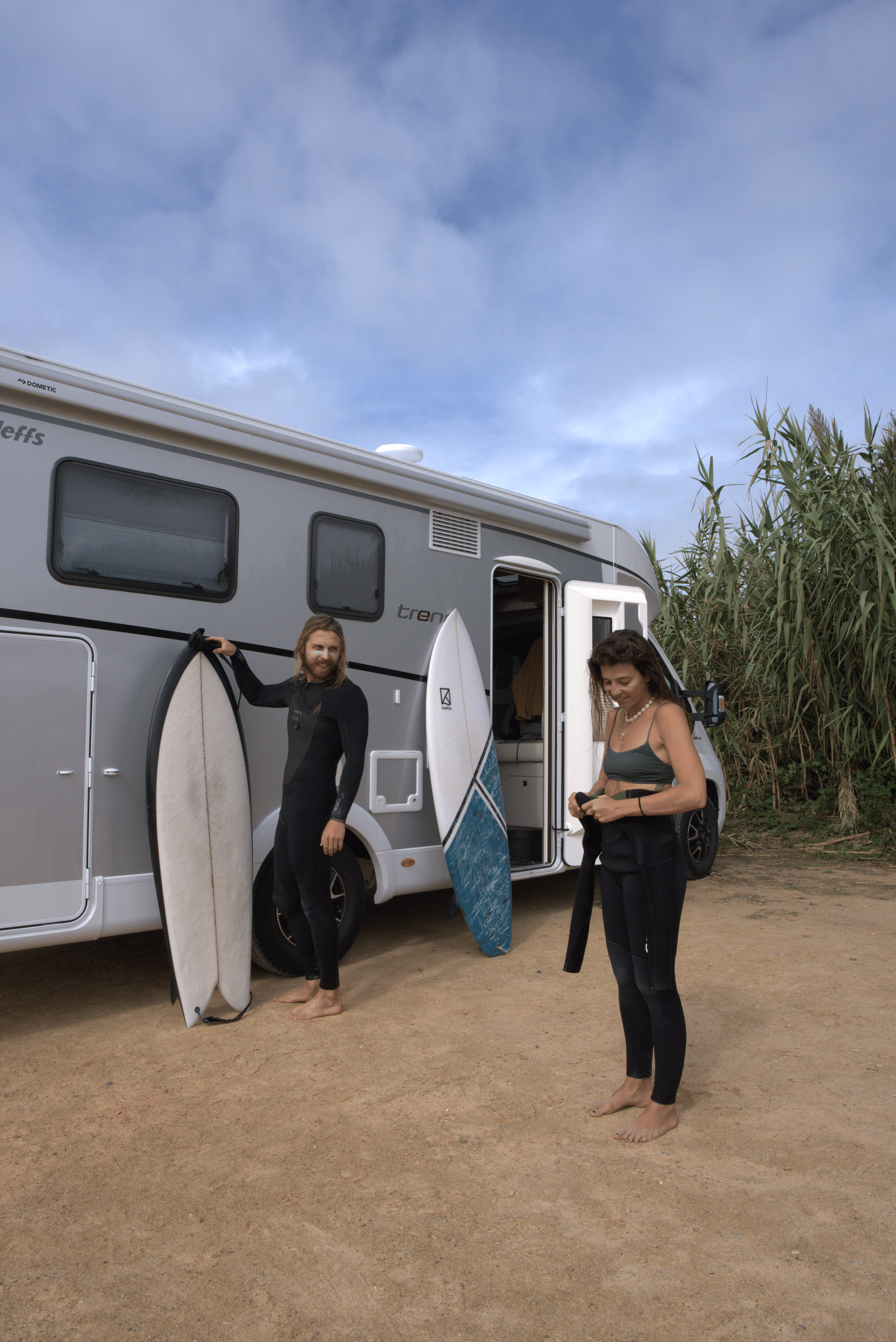 Paar mit Wohnmobil und Surfbrett in Portugal