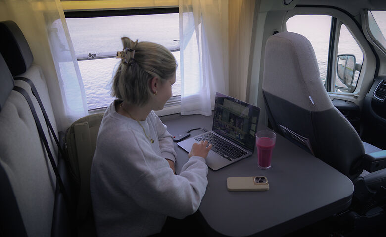 Frau arbeitet am Laptop im Camper 