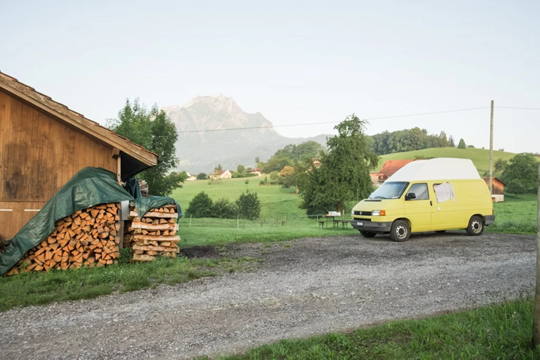 Gelber Camper parkt vor einem Biohof in der Natur
