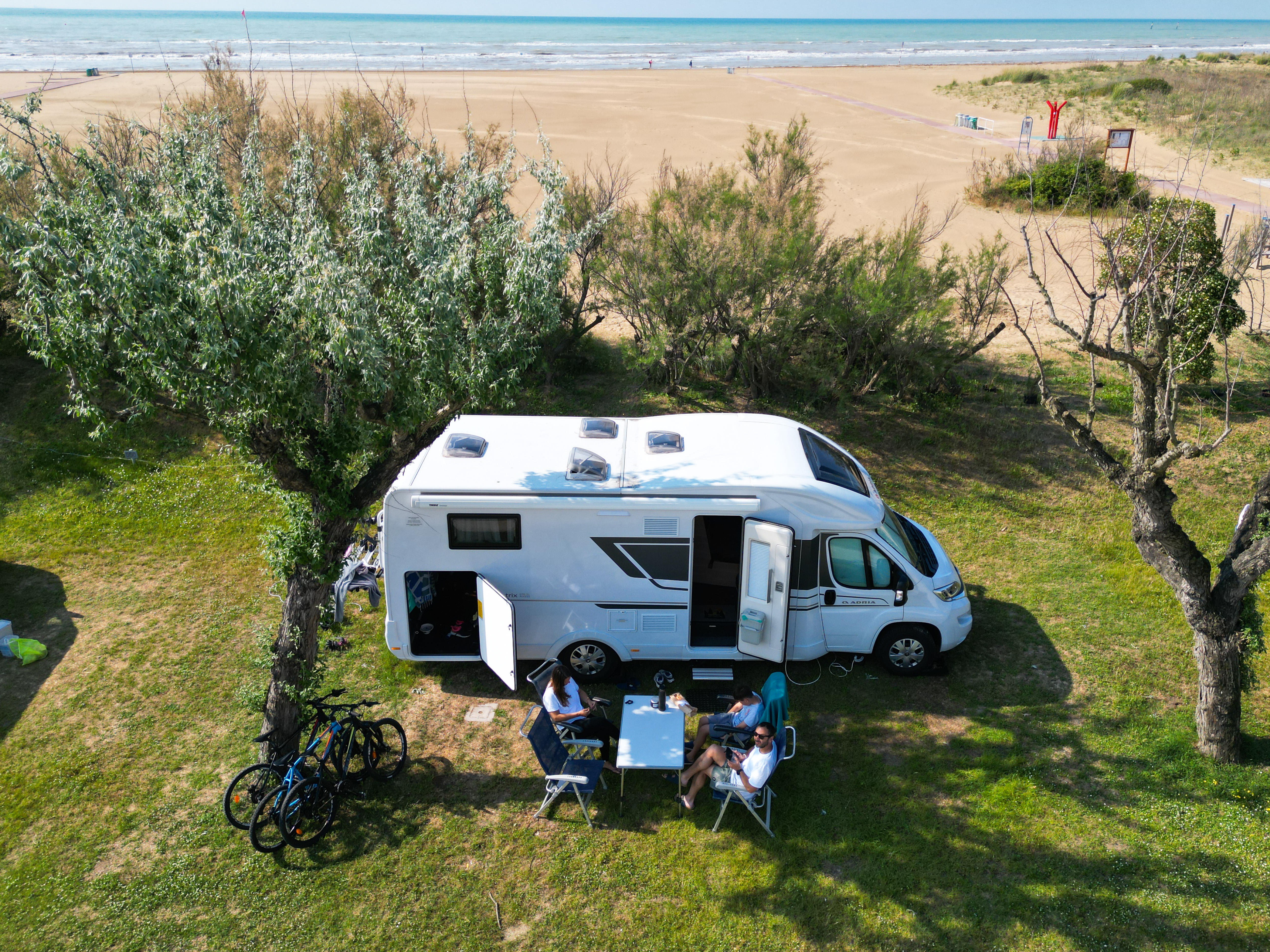 Menschen sitzen vor einem Camper und entspannen in der Sonne 