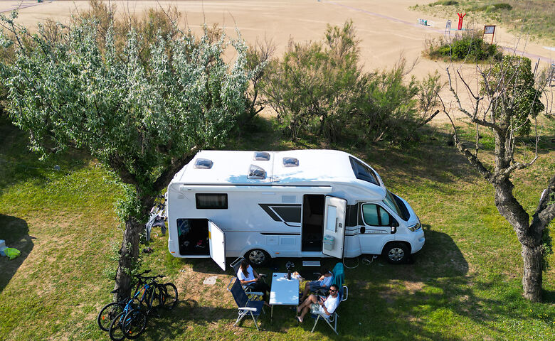Menschen sitzen vor einem Camper und entspannen in der Sonne 