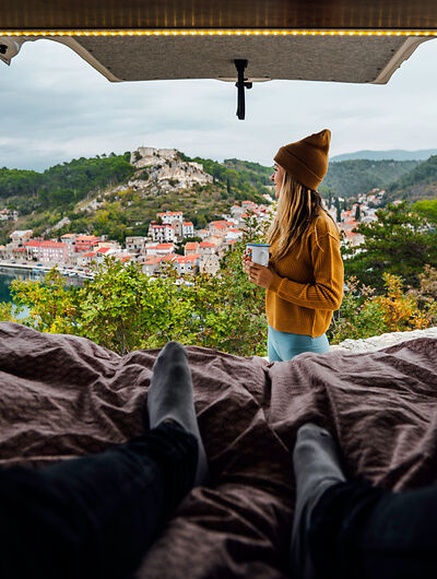 Frau mit Camper in Kroatien blickt auf Bergstadt