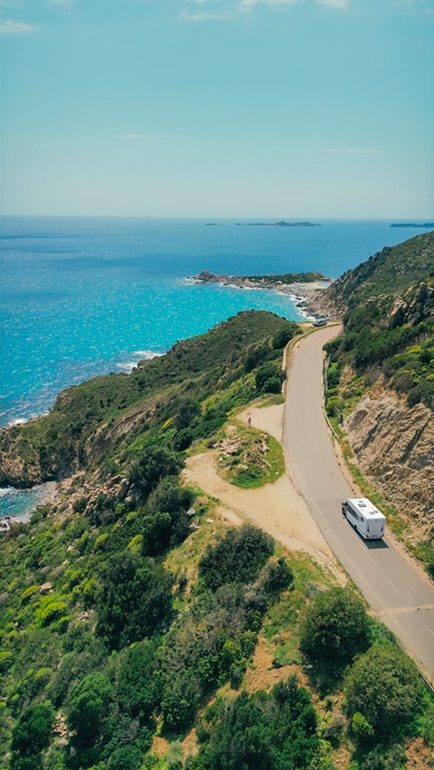Wohnmobil fährt auf einer Küstenstraße auf Sardinien entlang