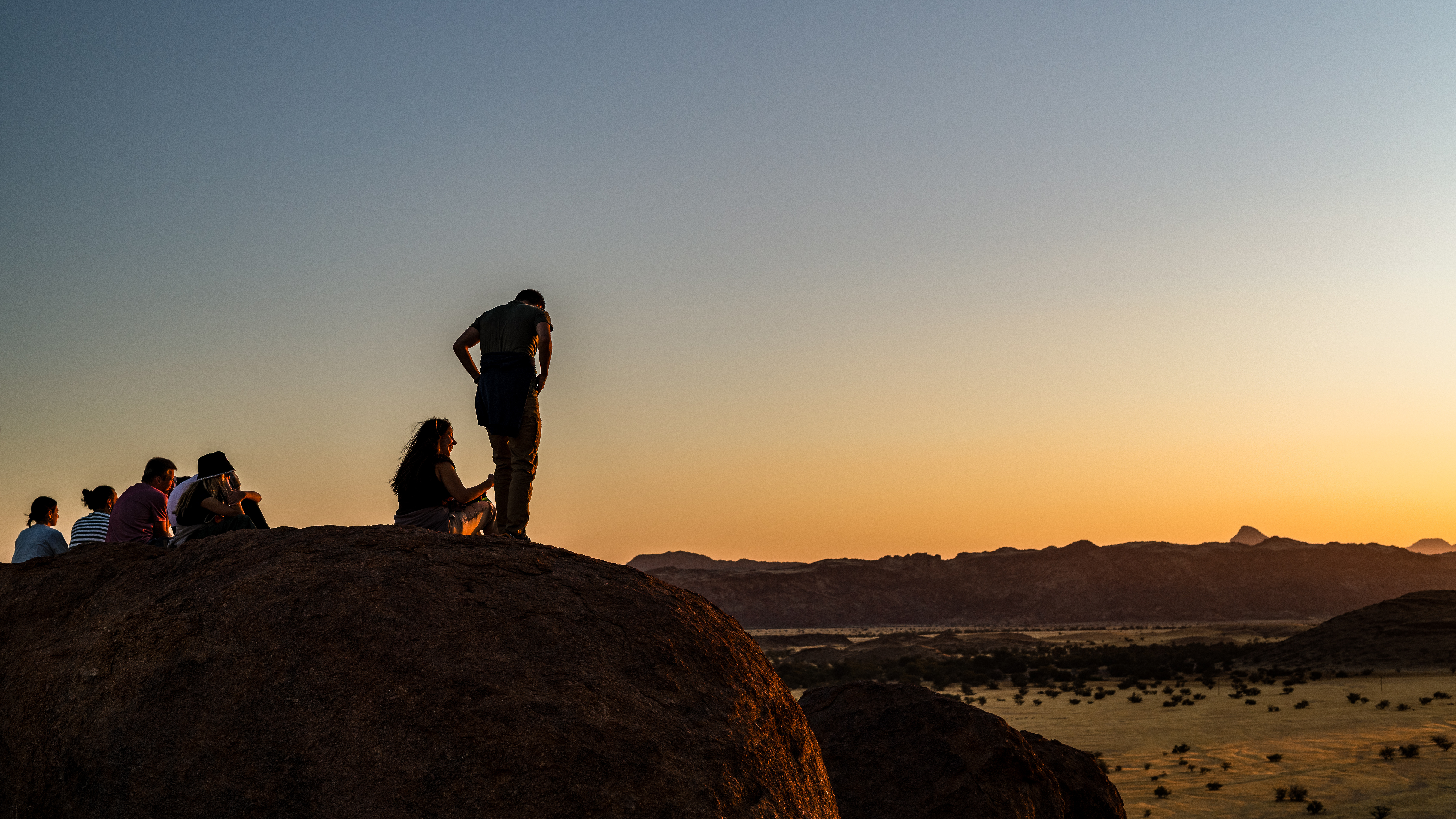 Menschen schauen sich Sonnenuntergang in Namibia im Damaraland an