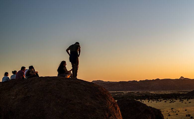 Menschen schauen sich Sonnenuntergang in Namibia im Damaraland an