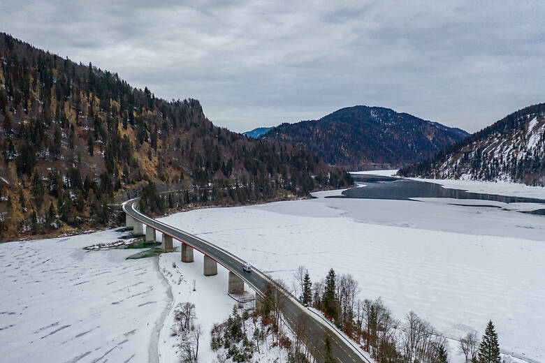 Wohnmobil fährt über den zugefrorenen Sylvensteinspeicher im Winter
