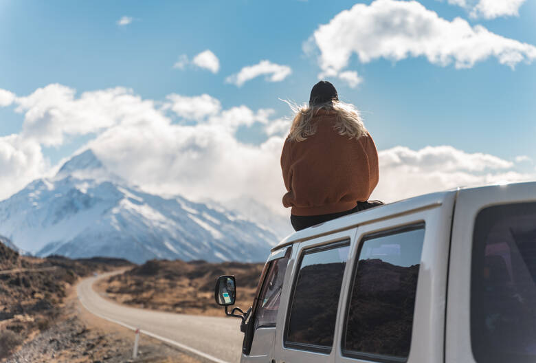 Frau sitzt auf einem Camper in Neuseeland 