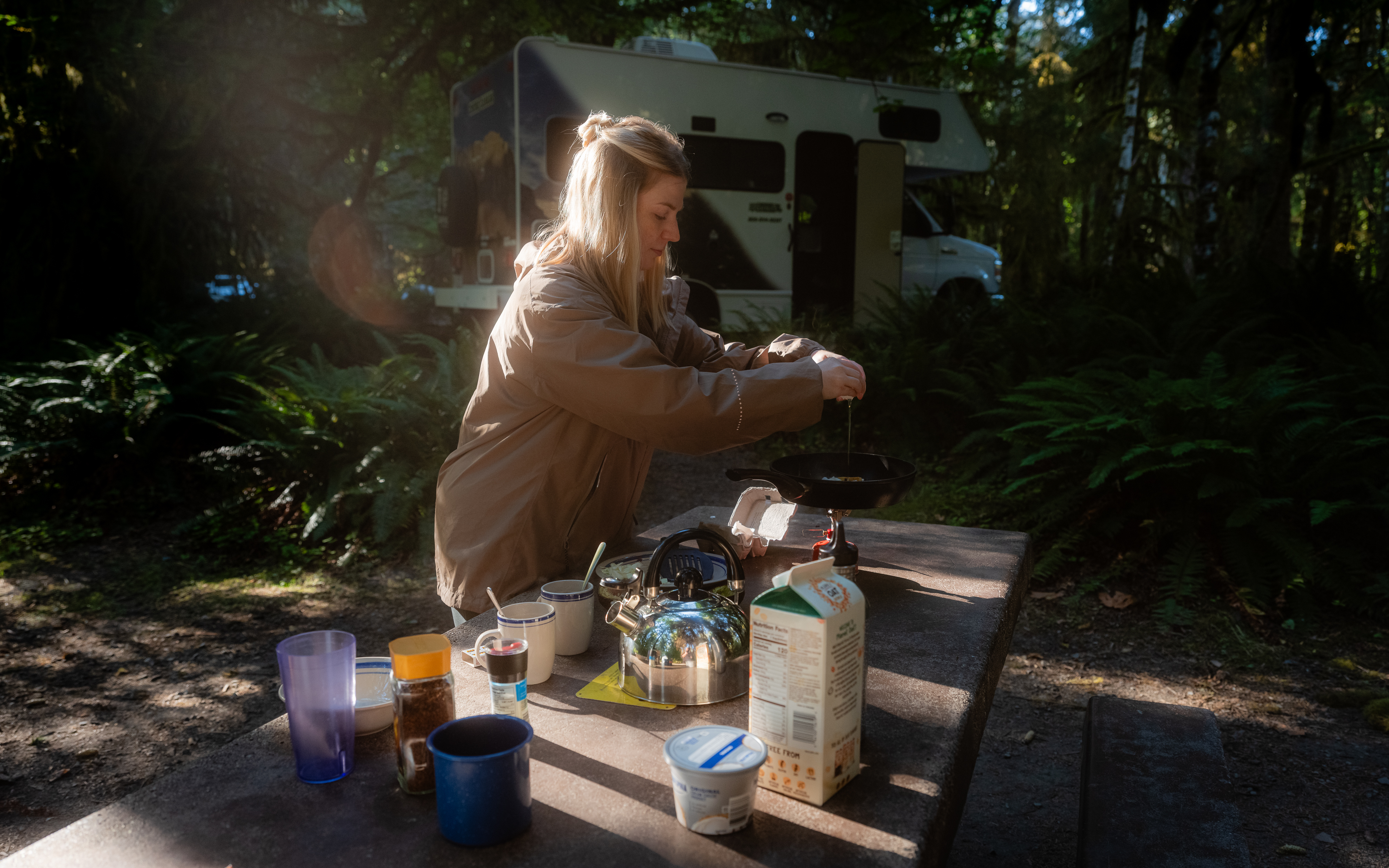Frau bereitet Frühstück auf dem Campingplatz vor