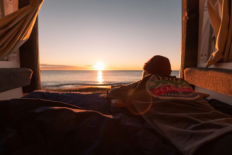 Mann beobachtet Sonnenuntergang vom Camper aus