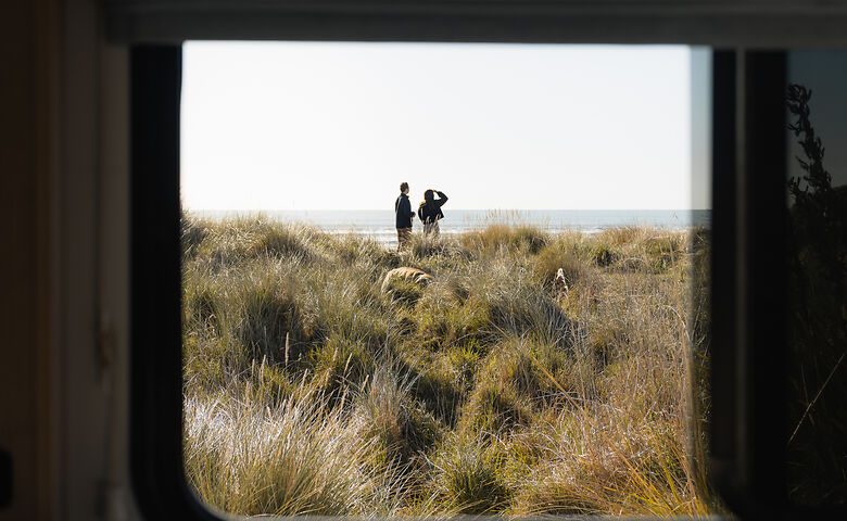 Blick aus dem Camper auf zwei Menschen am Meer in Neuseeland 