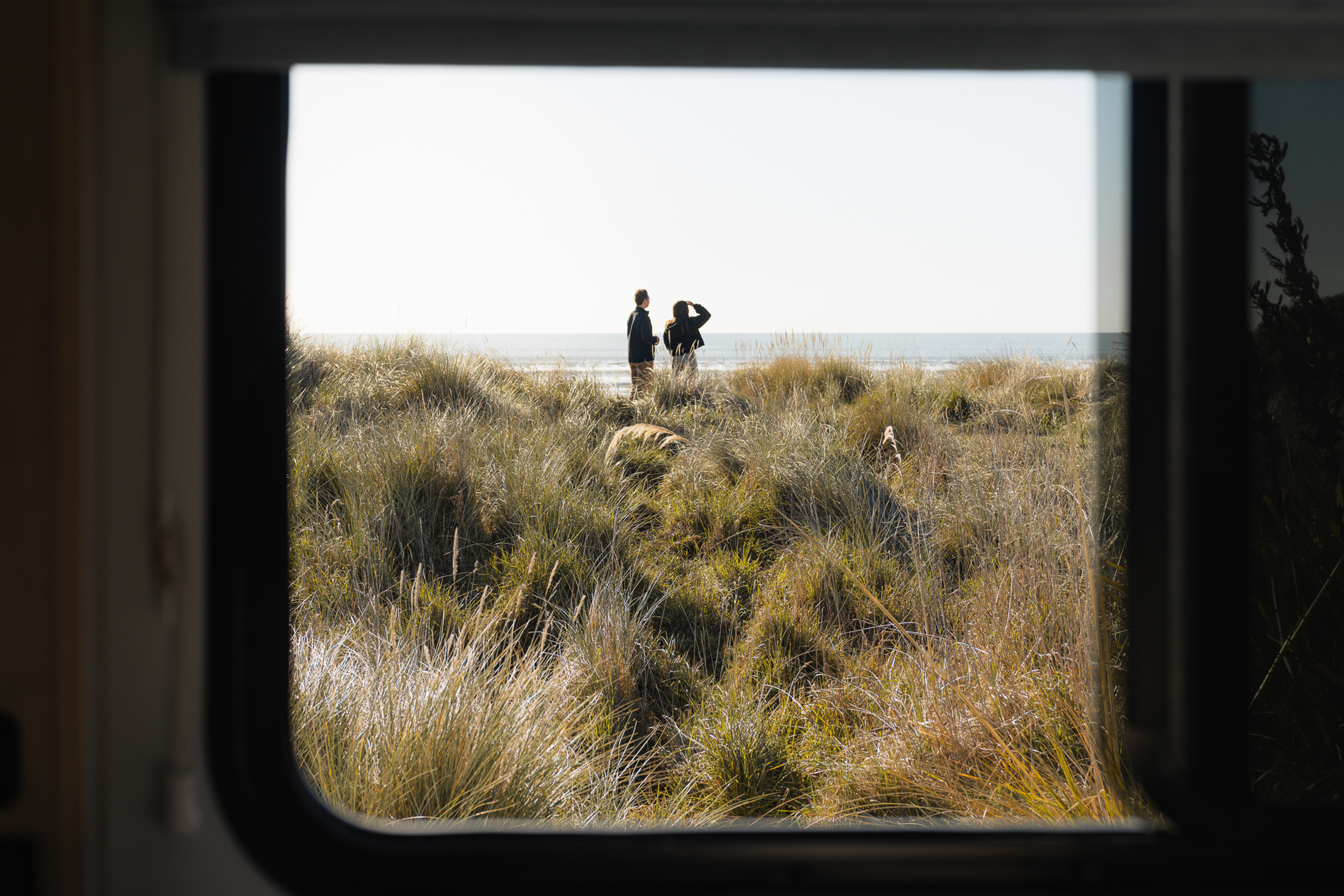 Blick aus dem Camper auf zwei Menschen am Meer in Neuseeland 