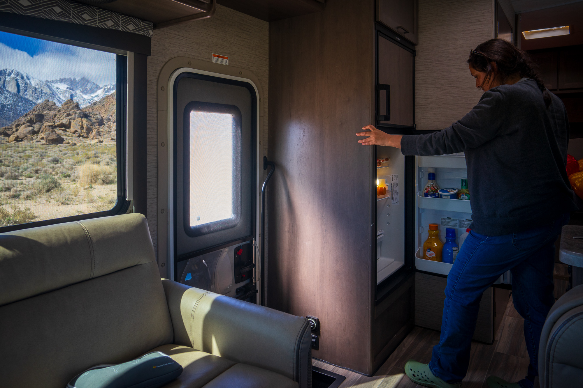 Frau öffnet Kühlschrank im Wohnmobil