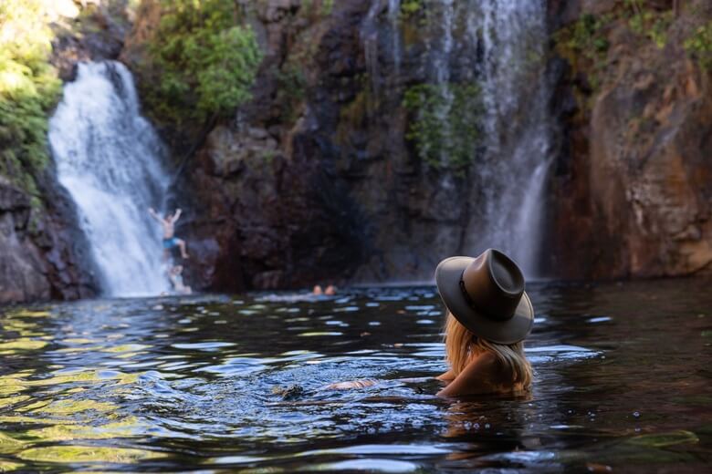Frau schwimmt in einem Felsenpool in Nordaustralien mit Blick auf einen Wasserfall