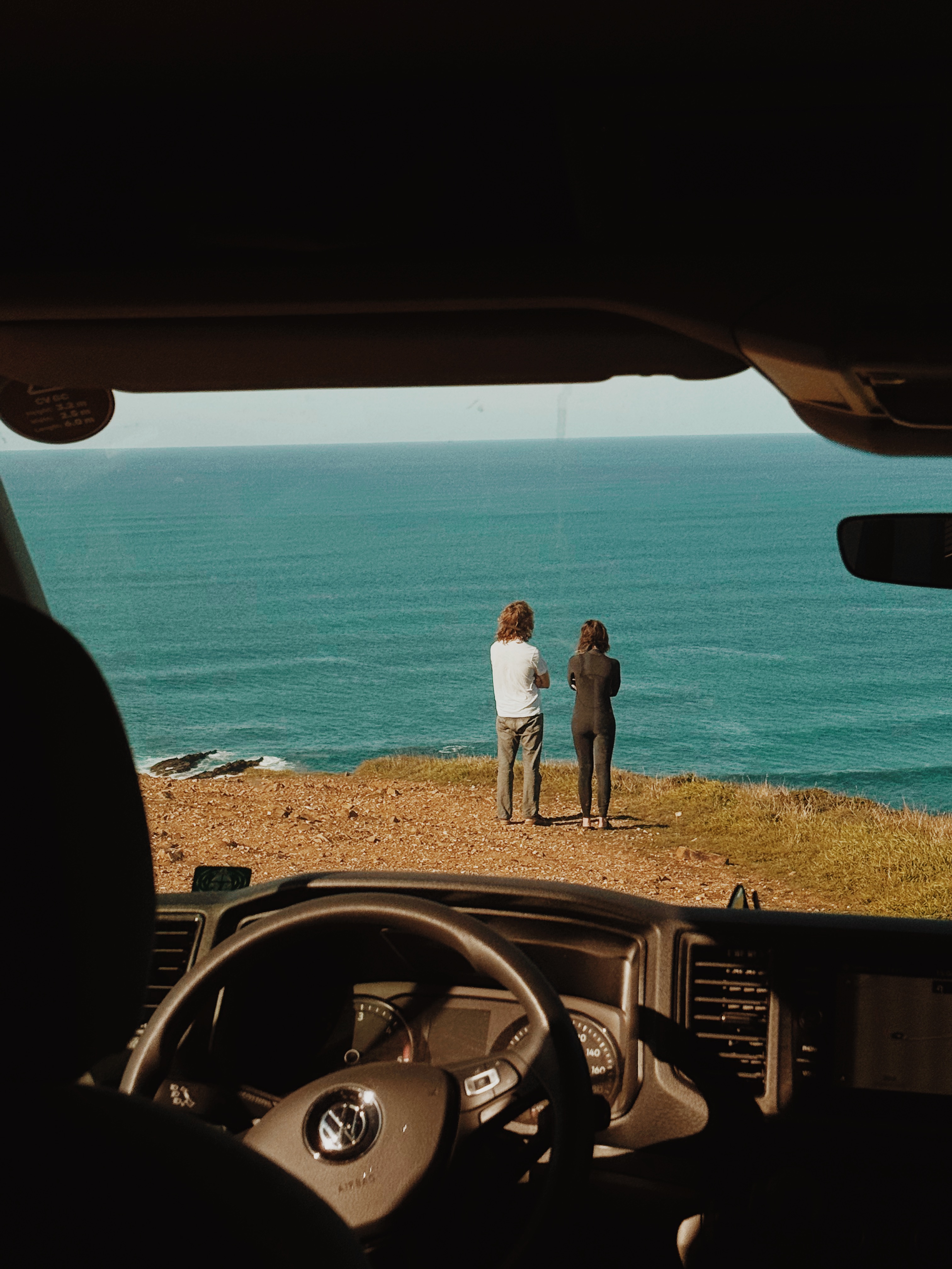 Mann und Frau stehen an der Algarve und schauen auf das Meer