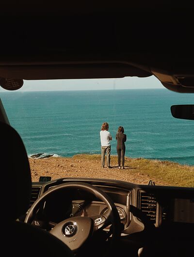 Mann und Frau stehen an der Algarve und schauen auf das Meer