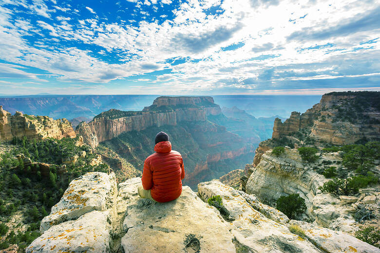 Mann mit einer roten Jacke blickt auf den Grand Canyon
