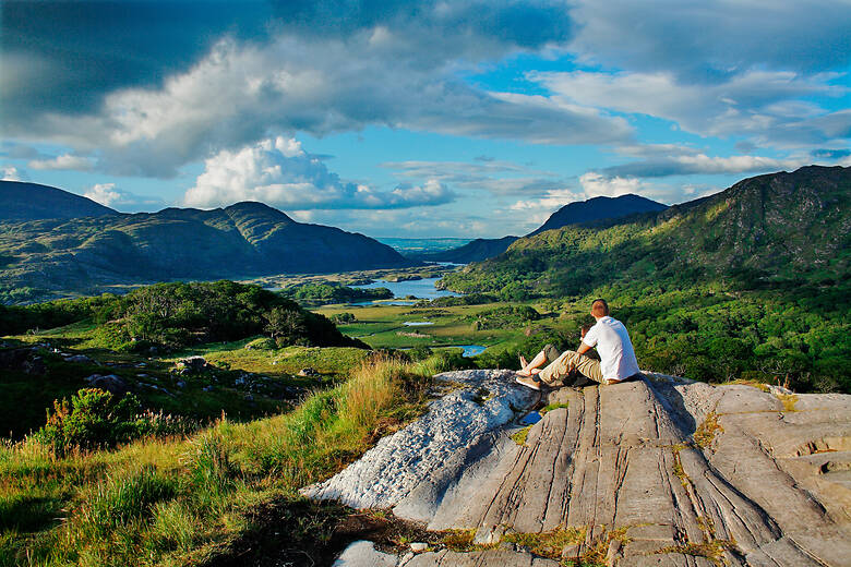 Paar blickt von einem Felsen über den Connemara-Nationalpark in Irland bis aufs Meer