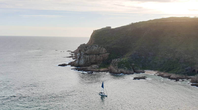 Segelboot fährt zwischen Klippen in den Hafen von Knysna ein