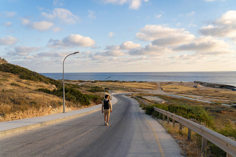 Mann läuft auf einer Straße zu einem Strand auf Zypern