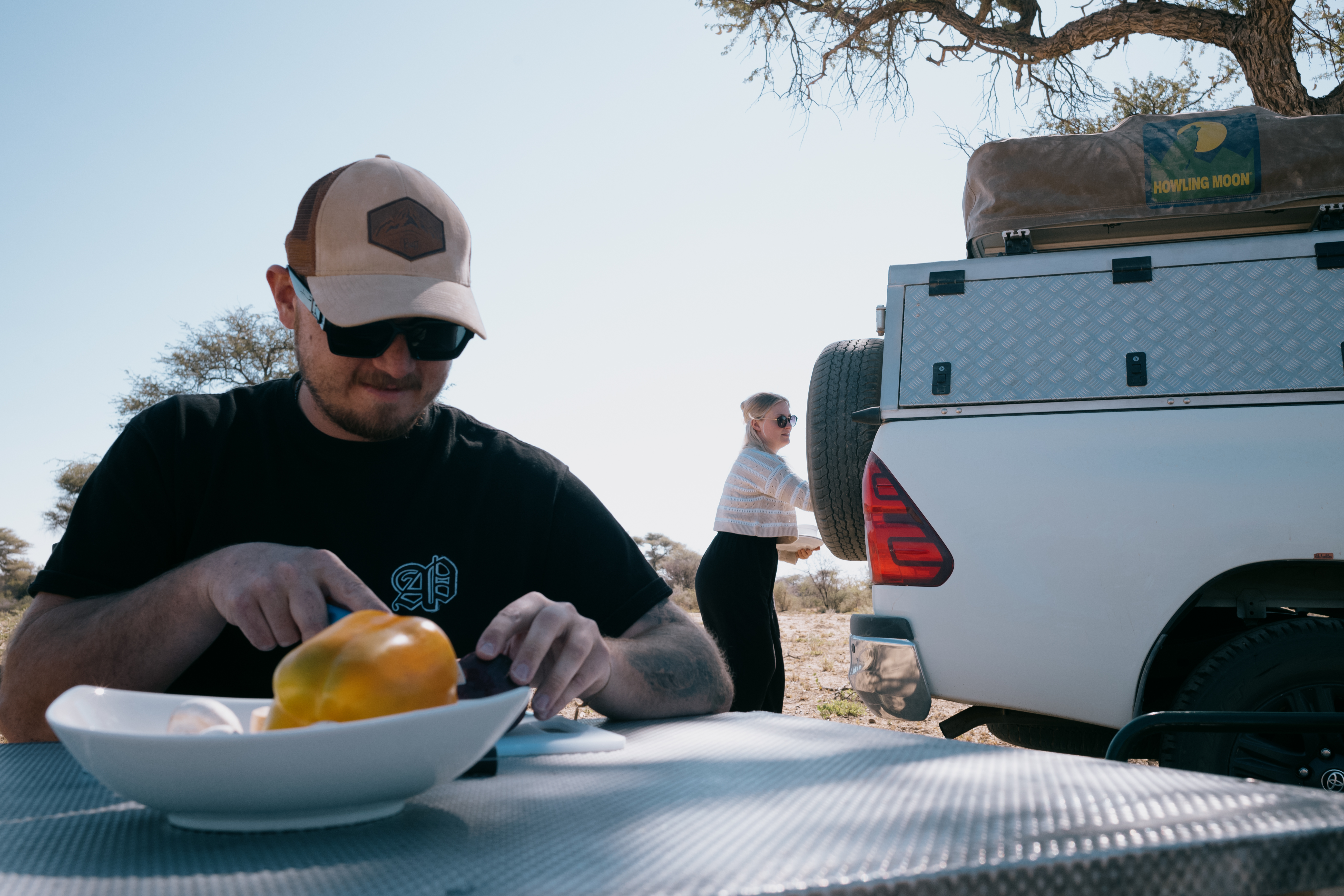 Mann schneidet Gemüse, Camper im Hintergrund