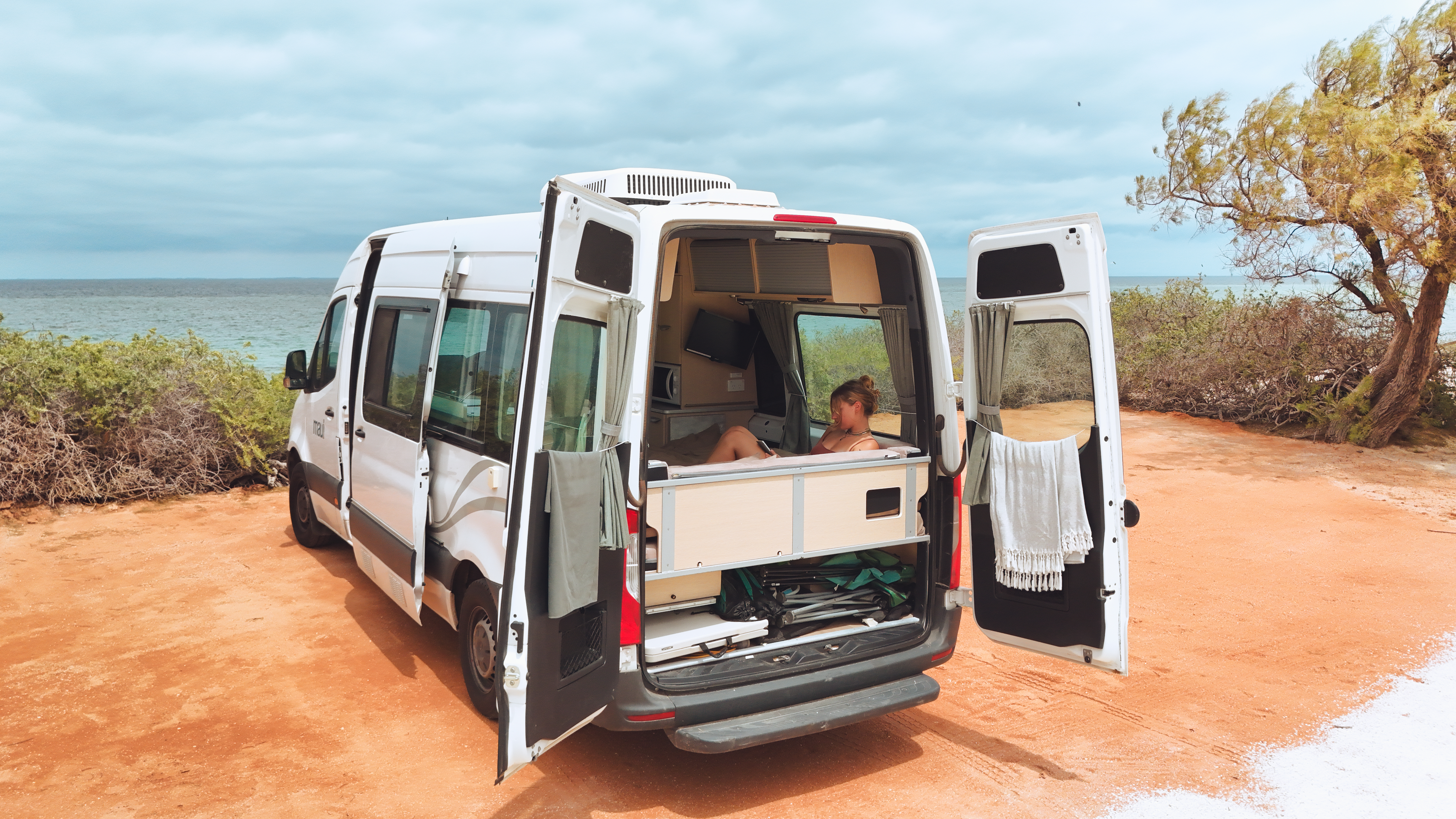 Frau entspannt im Camper am Meer