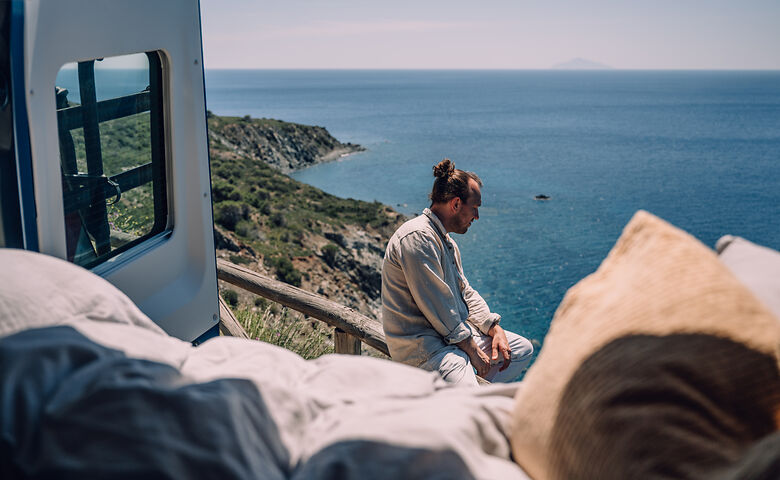Mann am Camper schaut auf das Meer