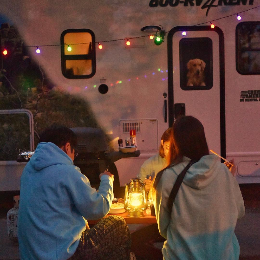 Freunde essen gemeinsam vor dem Wohnmobil