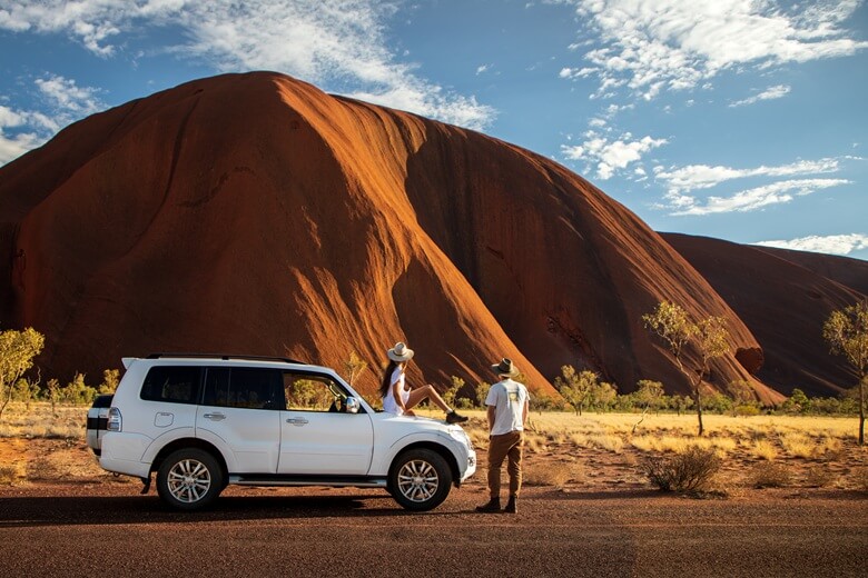 Frau und Mann stehen mit einem Campervan im australischen Outback