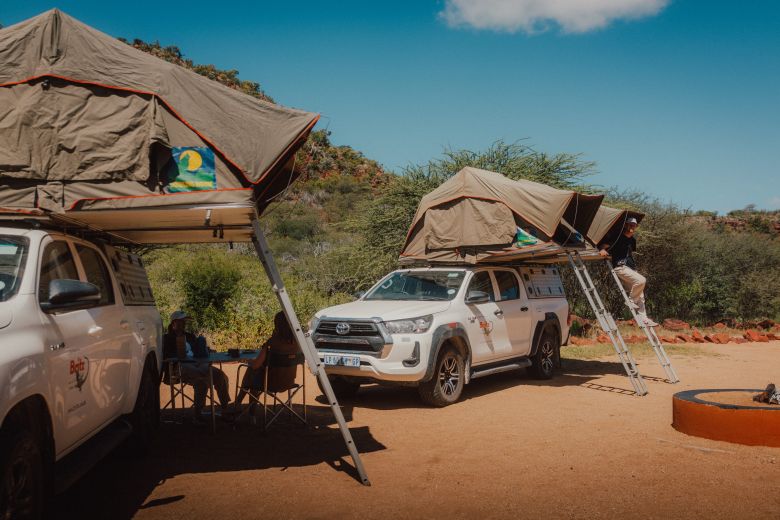 Mann steigt aus einem Dachzelt-Camper in Namibia auf einem Campingplatz