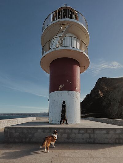 Una mujer hace el pino en un faro en España.