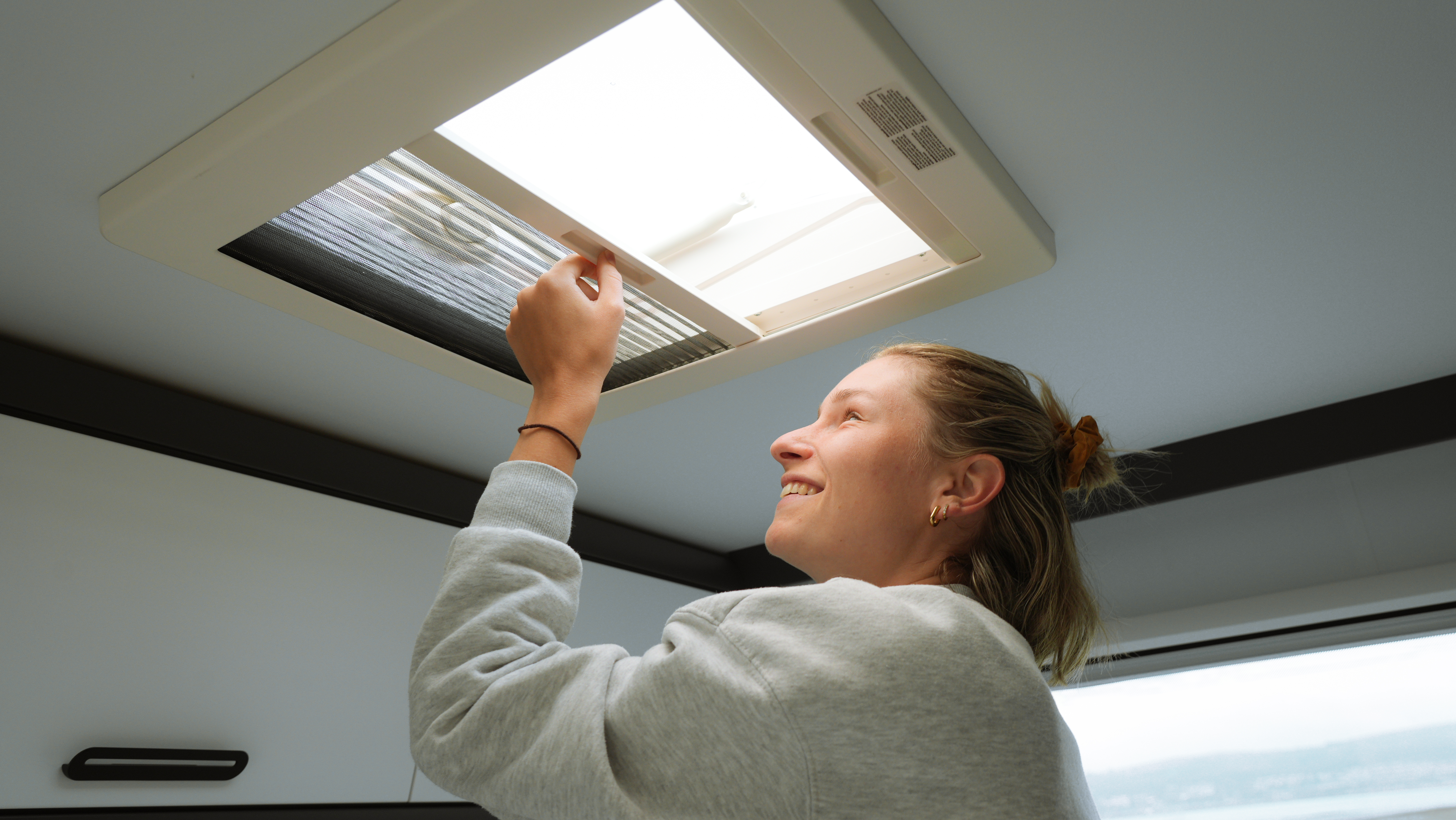 Frau schließt Dachfenster im Wohnmobil