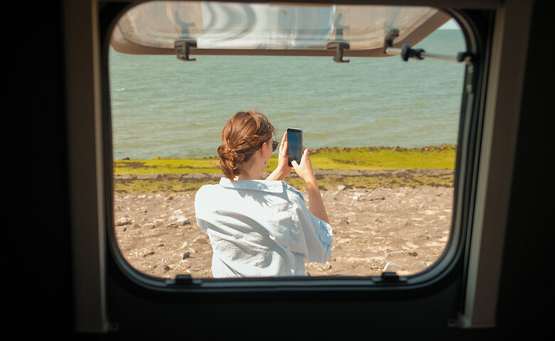 Frau fotografiert das Meer, Blick aus dem Wohnmobil