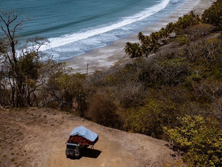 Camper mit Dachzelt steht an einem Strand an der Küste von Costa Rica