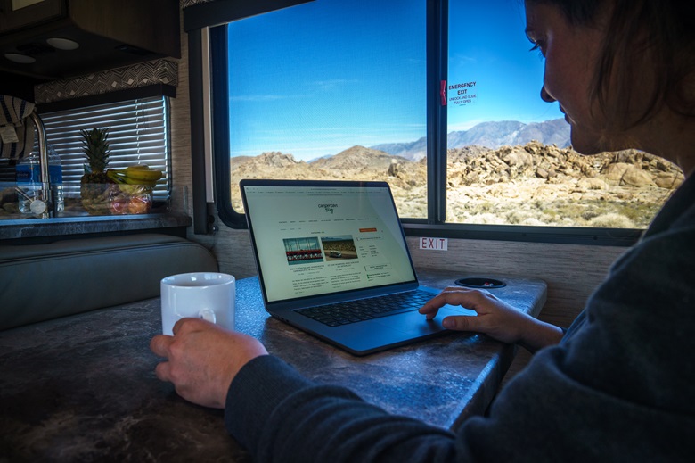 Frau mit Laptop und einer Kaffeetasse im Wohnmobil