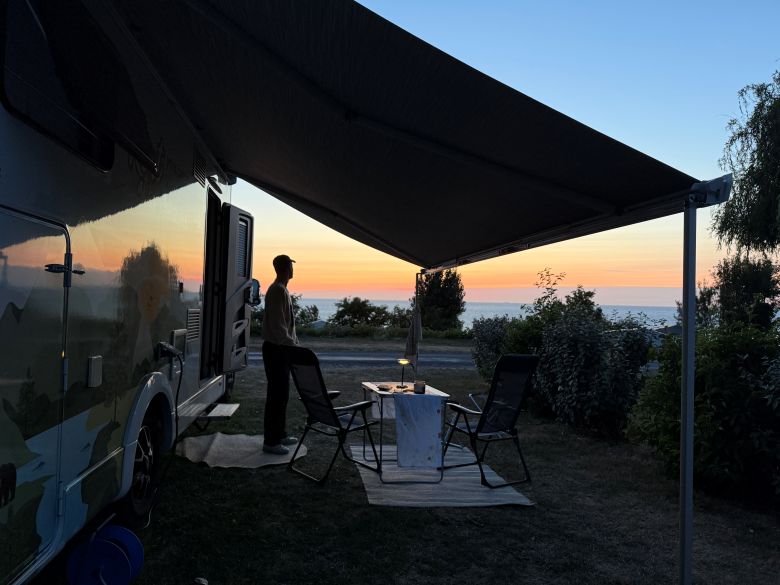 Mann auf einem Campingplatz an der Normandie bei Sonnenuntergang 