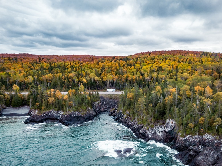 Wohnmobil fährt durch eine herbstliche Landschaft in Kanada am Meer