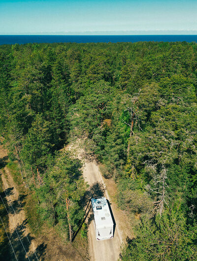 Wohnmobil zwischen Bäumen und mit Blick auf das Meer in Estland 