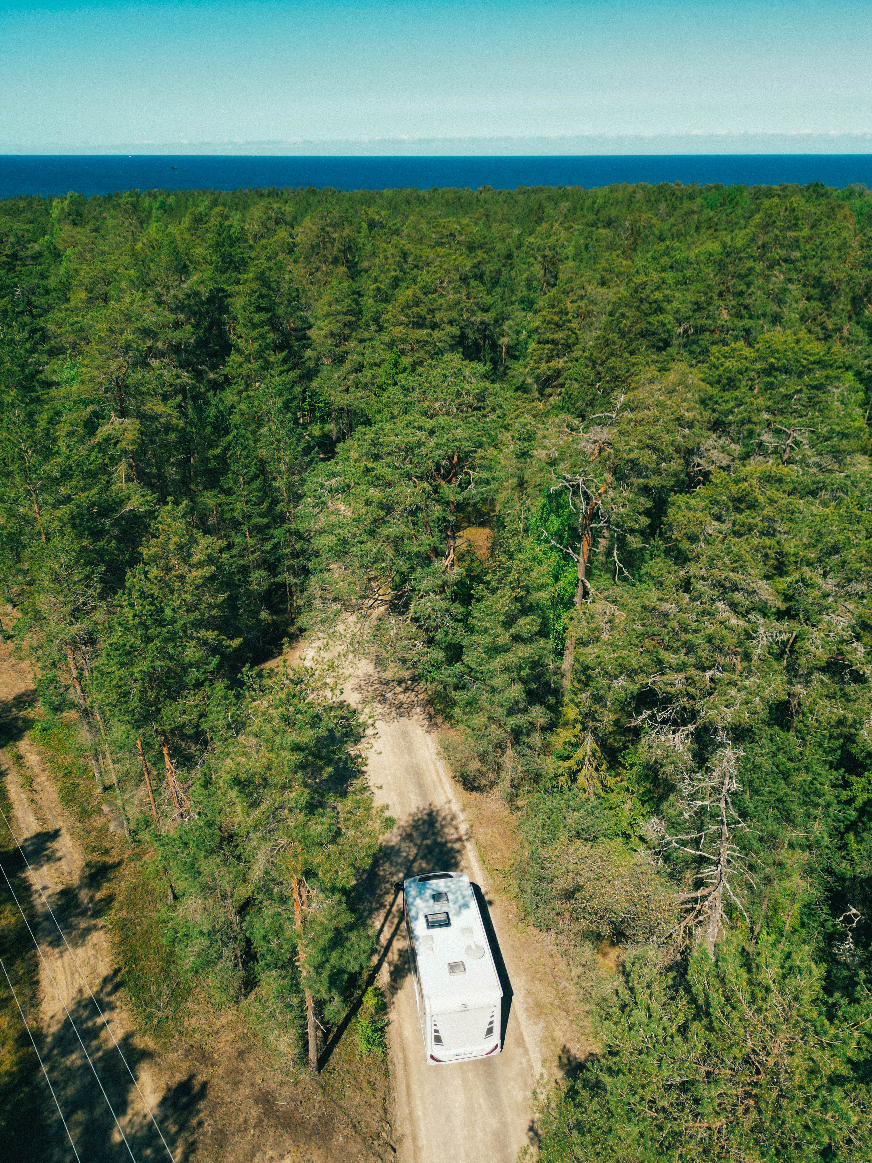 Wohnmobil zwischen Bäumen und mit Blick auf das Meer in Estland 