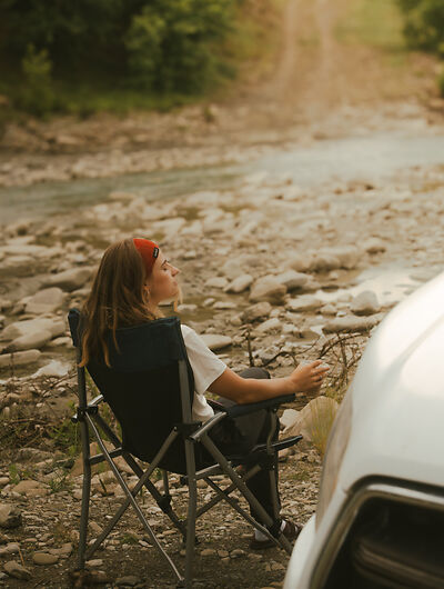 Frau entspannt vor dem Camper in der Sonne 