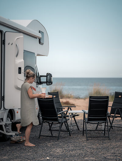 Frau am Strand in Finnland mit Wohnmobil