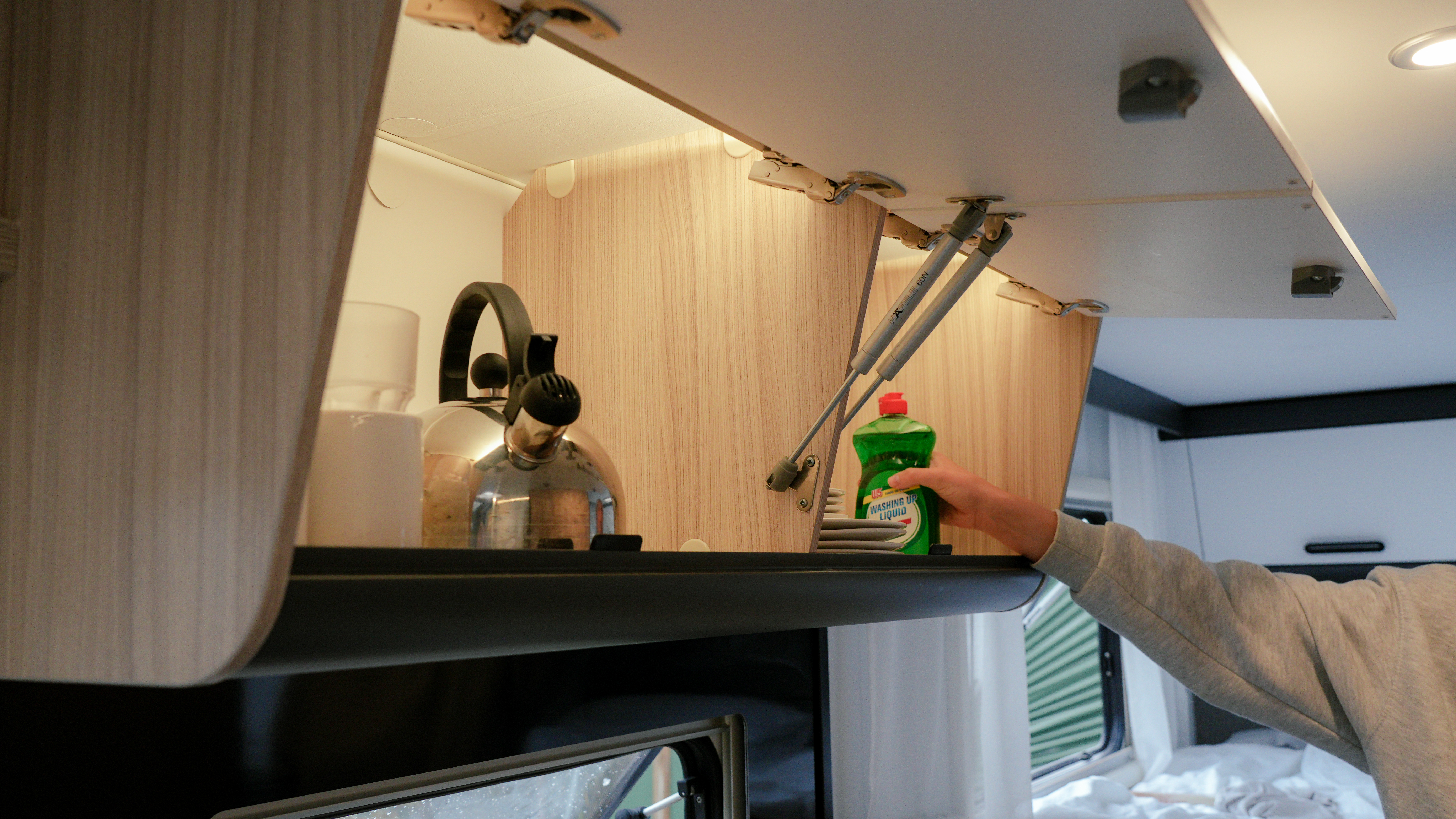 Hand greift nach dem Spülmittel im Wohnmobil