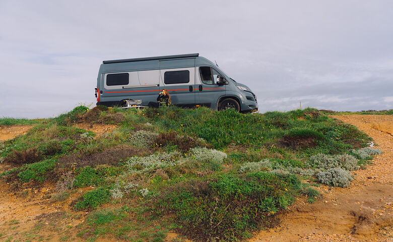 Frau campt mit dem Wohnmobil am Meer in Portugal
