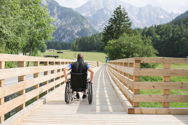 A man in a wheelchair roll across a wide bridge