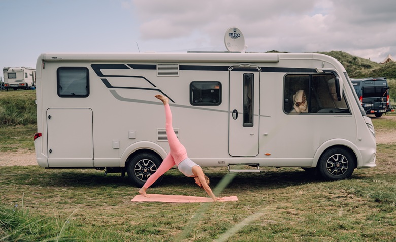 Frau macht Yoga vor einem Wohnmobil